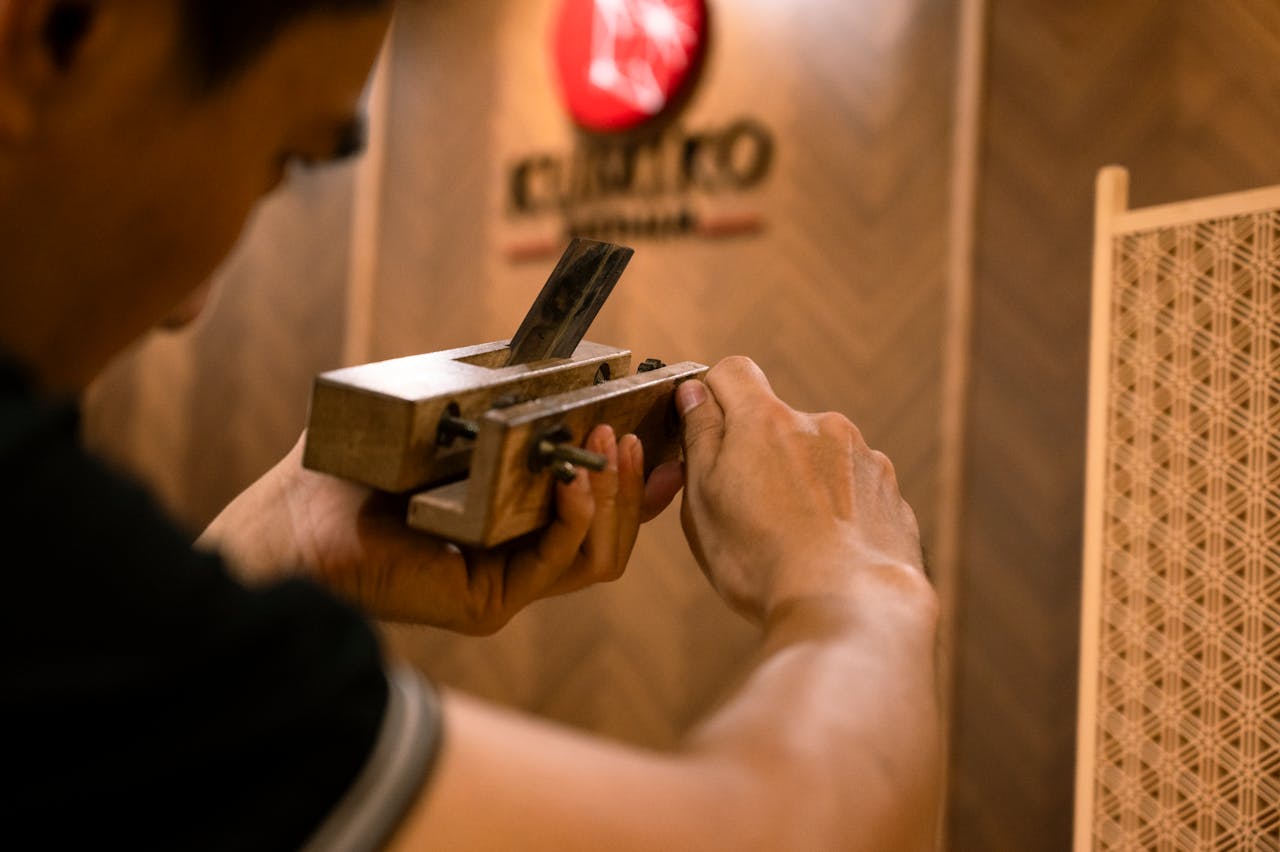 Close-up of a craftsman using a traditional Japanese hand plane in a workshop setting.